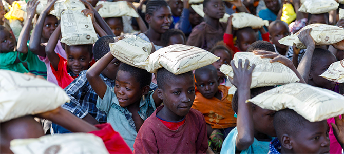 670x300_Day4_05_NuSkin A group of underprivileged children carry bags of VitaMeal on their heads.