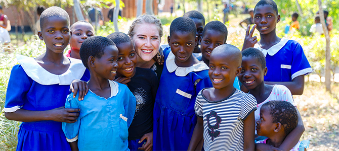670x300_Day3_01_NuSkin copy Nu Skin Employee Emily Sander poses for a picture with a group of children from Malawi.